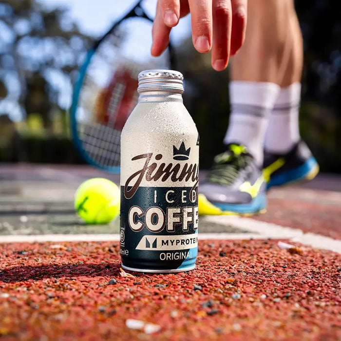 Hand reaching for a bottle of Jimmy's Iced Coffee - Myprotein Original Big BottleCan 380ml on a tennis court