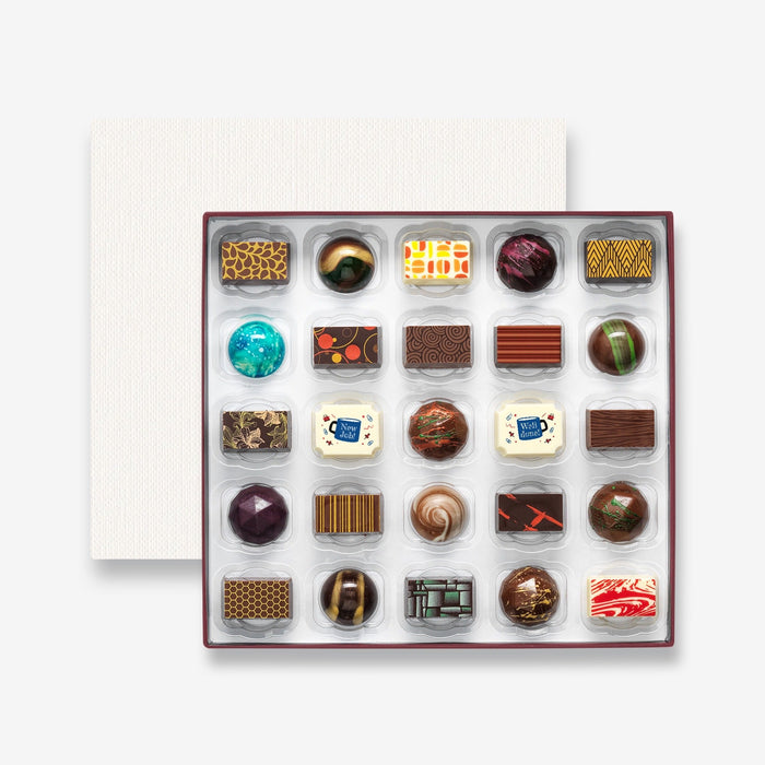 An open chocolate selection box containing 25 chocolates made by Harry Specters. The chocolates seen within this gift box are a colourful mix of white, milk, and dark chocolate with two New Job message chocolates.