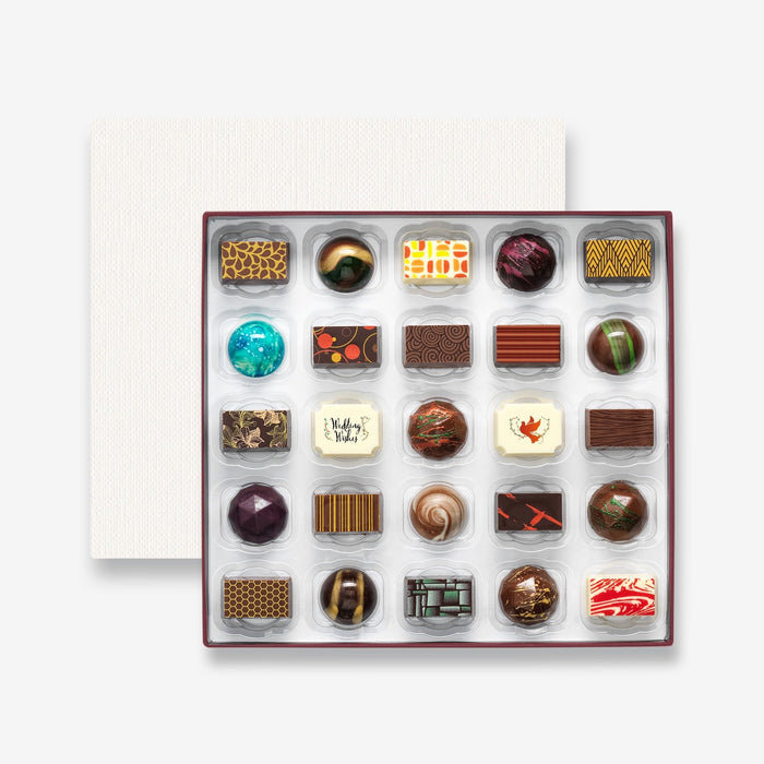 An open chocolate selection box containing 25 chocolates made by Harry Specters. The chocolates seen within this gift box are a colourful mix of white, milk, and dark chocolate with two Wedding Wishes message chocolates.