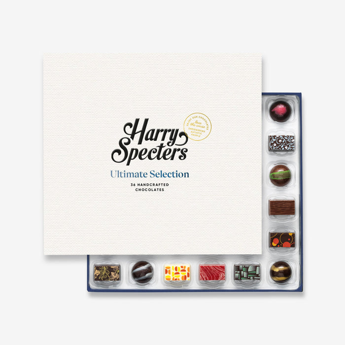 A Christmas chocolate selection box containing 36 chocolates, partially covered by a lid showing the name Harry Specters. The chocolates seen within this gift box are a colourful mix of white, milk, and dark chocolate with two Merry Christmas message chocolates.