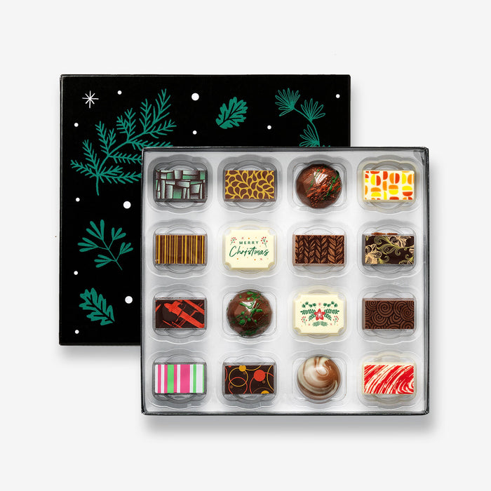 An open Christmas chocolate selection box containing 16 chocolates made by Harry Specters. The chocolates seen within this gift box are a colourful mix of white, milk, and dark chocolate with two Merry Christmas message chocolates.