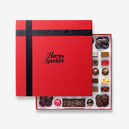 A chocolate selection box containing 55 chocolates, partially covered by a lid showing the name Harry Specters. The chocolates seen within this gift box are a colourful mix of white, milk, ruby, caramel, and dark chocolate, with coffee beans, mini chocolate bars, and hot chocolate buttons with two Engagement themed chocolates.